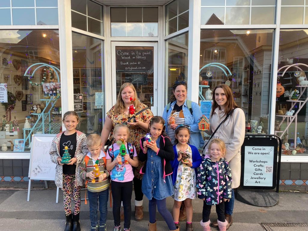 mothers and children standing outside arty boat showing their painted creations after a fun day out 