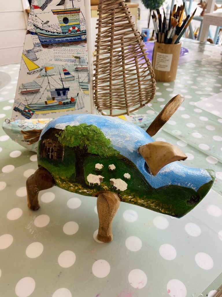 painted wooden pig in style of a farm and the sky